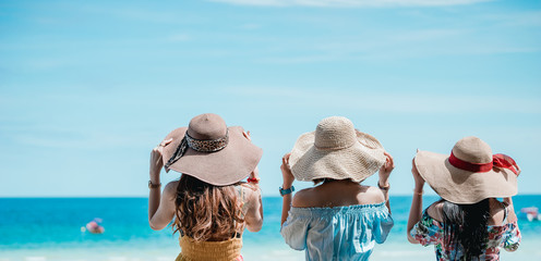 Young woman wearing Hawaiian with hat and sunglasses is happy when they go to the beach for a holiday.