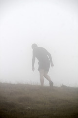 Hombre subiendo una montaña en un día con niebla