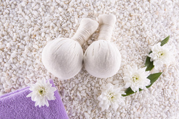 Fototapeta na wymiar Spa. Still life. Herbal balls, a towel and flowers on a background of white pebbles.