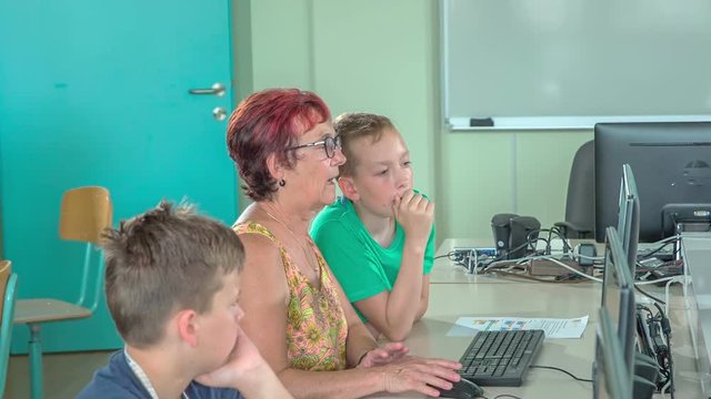 Grandkids and their grand children are learning computer basics together in a computer lounge in school. 