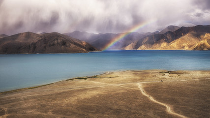 the lake is raining day with sunlight is rainbow, the biker riding on the way to see a beautiful scenic