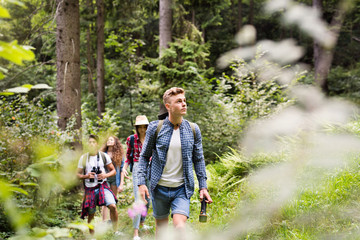 Teenagers with backpacks hiking in forest. Summer vacation.