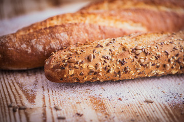 Macro view of fresh crunchy baguette bread with sunflower seeds and other seeds on the rustic wooden desk2