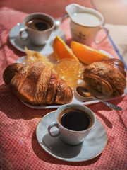 Delicious continental breakfast with fresh flaky croissants, assorted preserves, orange jam and coffee with milk, close up on the cup of coffee01
