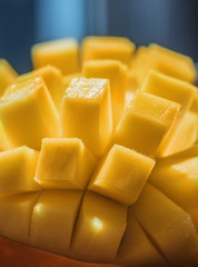 Natural Fresh Ripe Mango cubes, Slices close up, Macro shooting. On the dark blue or black background. On the rustic wooden board and bamboo napkin 01