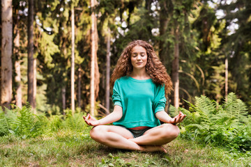 Beautiful girl practices yoga in the morning forest.
