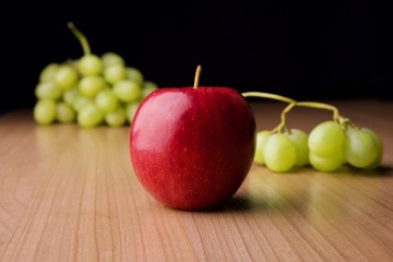 A red apple and green grapes on the table