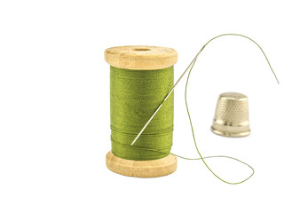 Isolated wooden spool of green thread with a needle