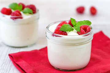 White yogurt with fresh raspberries in glass bowl.