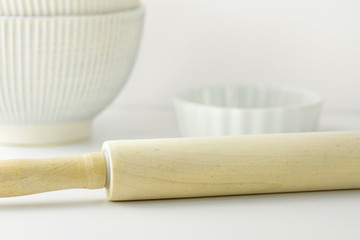 Wooden rolling pin, white bowl and baking form on table top. Pastry, cooking, bakery concept. Clean minimalist style. Template for poster, menu, banner. Copy space, text ready.