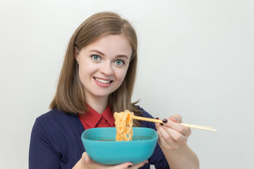 Young caucasian girl eating noodles using chopsticks