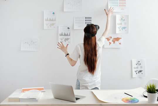 Woman working with virtual reality glasses on analitical reports at the office