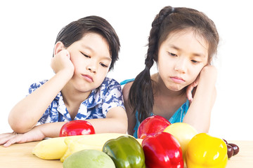 Fototapeta premium Asian boy and girl showing dislike expression with fresh colorful vegetables isolated over white background