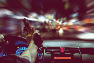 Fototapeta premium Man drink beer while driving at night in the city dangerously, left hand drive system