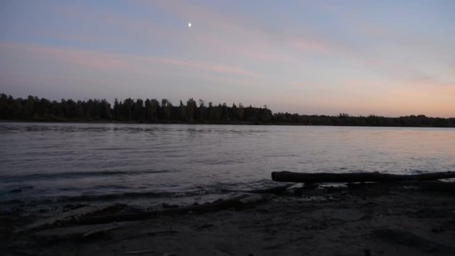 Smooth river, trees on the opposite bank, moon in the sky, small clouds, trees and sky s reflection in the water, outdoor, autumn, summer, evening