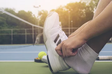 Poster Tennis player is putting shoe before the match in tennis hard court © pairhandmade