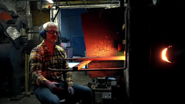 Blacksmith examining metal in furnace