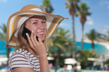 Fototapeta premium Young girl in bonnet hat calling by phone against wonderful sea view. Santa Susanna. Cataluna. Spain.