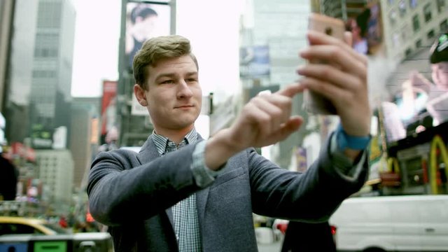 Young man taking a picture of himself on Times Square on a smartphone camera