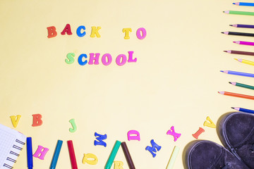 colorful letters back to school and colorful pen black shoes on yellow background