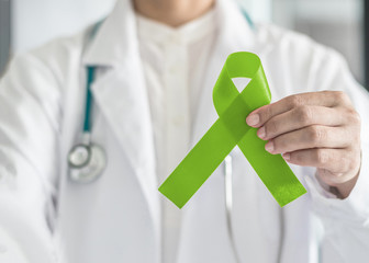 Lime green ribbon in doctor’s hand for Lymphoma cancer and mental health awareness, raising support and help patient living with illness
