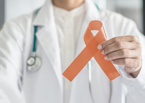 Uterine and Gynecologic Cancer Awareness peach color ribbon (isolated with clipping path) in doctor’s hand