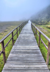 Fototapeta na wymiar Wooden walkway that leads to the Limpiopungo Lake in the Cotopaxi National Park, on an overcast and foggy rainy day, Ecuador.