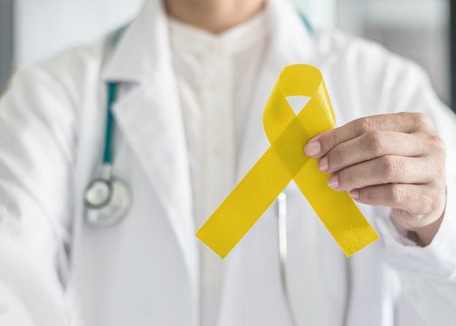 Yellow ribbon symbolic color for Sarcoma Bone cancer awareness and suicide prevention in doctor’s hand