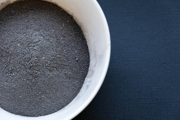 a bowl of black clay mask with brush at home skin care