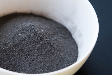 a bowl of black clay mask with brush at home skin care