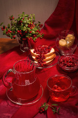 On a red background red foods and drinks. The still life includes fruit drink, jam, sandwich, twigs cowberry with berries.