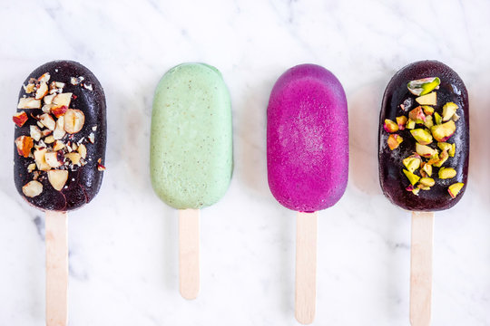 Flat lay with colorful popsicles on white marble table. Summer ice cream pattern