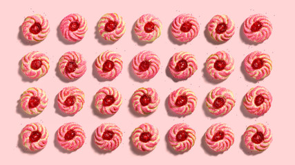 Overhead view of a colorful pattern of amaretti, cherry almond, cookies on pink background