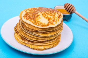 Stack of fresh delicious pancakes on white plate on blue backgro