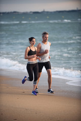 A couple wearing sportswear is running on the beach