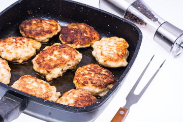 Frying pan with cutlets on white background