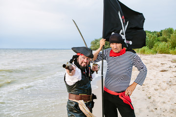 Two pirates with a flag on the seashore