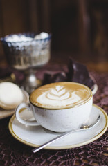 Coffee latte on the wooden retro table. Brekfast with chocolate and macaroons
