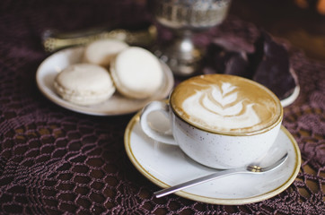 Coffee latte on the wooden retro table. Brekfast with chocolate and macaroons