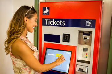 Beautiful young woman buying tickets for public transportation