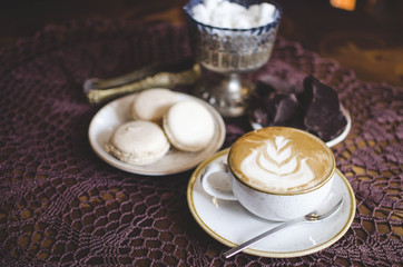 Coffee latte on the wooden retro table. Brekfast with chocolate and macaroons