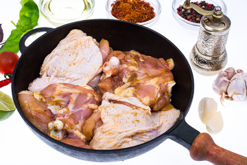 Cast-iron frying pan with marinated chicken thighs for frying