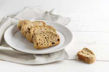 fresh wholemeal bread on a plate, on a white painted rustic wooden table, copy space