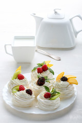 Homemade mini pavlova cakes with whipped cream and fresh berries on light  background.