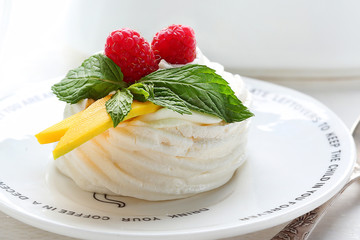 Mini Pavlova meringue nest with berries and mint on white background.