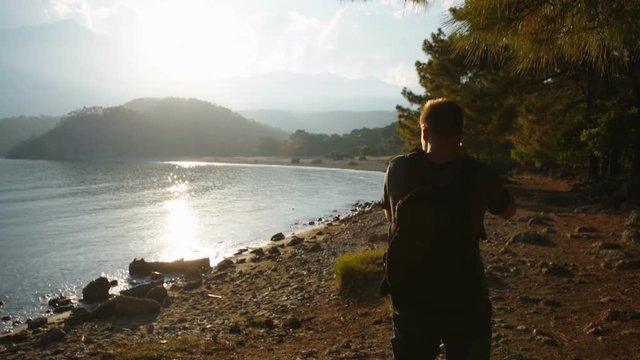 traveler photographer shoots beautiful sunset on the shore of a mountain lake