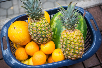 verschiedene reife Früchte in einem Plastikkorb auf Strassenpflaster