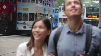 Hong Kong People walking in Central busy road with tramway. Urban mixed race Asian Chinese / Caucasian woman smiling happy living in city.