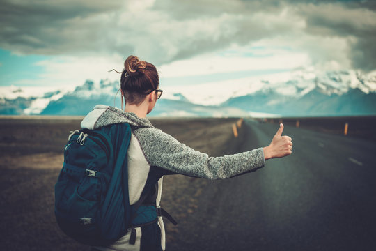 Travel hitchhiker woman walking on a road