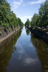 Fototapeta premium Kronstadt, Ruusia - July 16, 2014. A canal with green trees in Kronstadt. Kronstadt is city-fortress in the Baltic